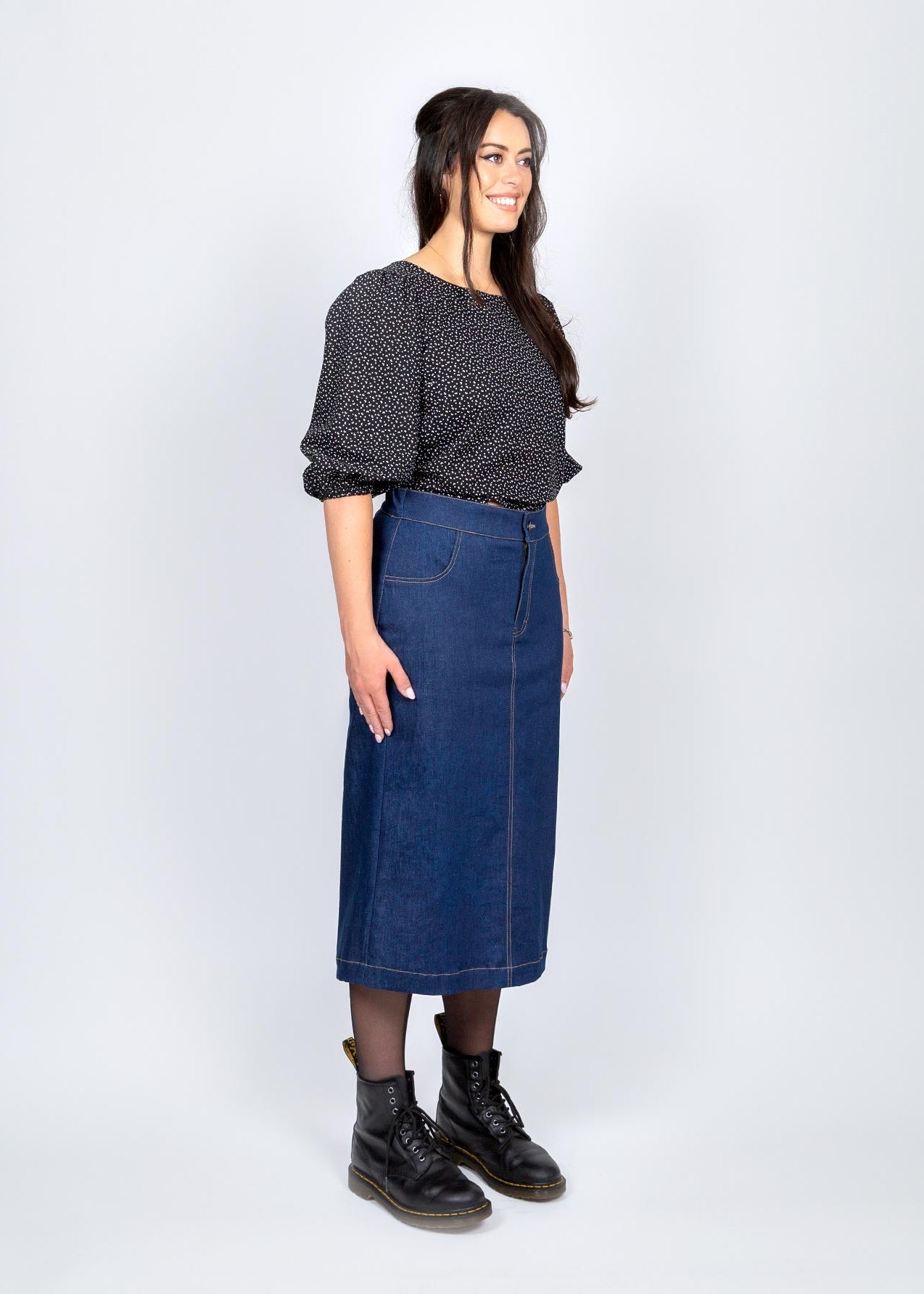 Woman wearing a dark denim skirt and black shoes on a white background